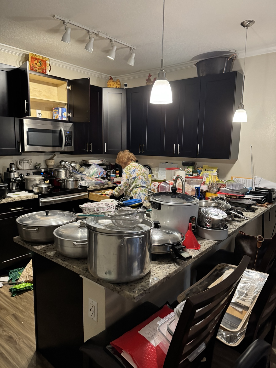 Condo kitchen counters and island covered with pots, pans and small appliances before contents removal