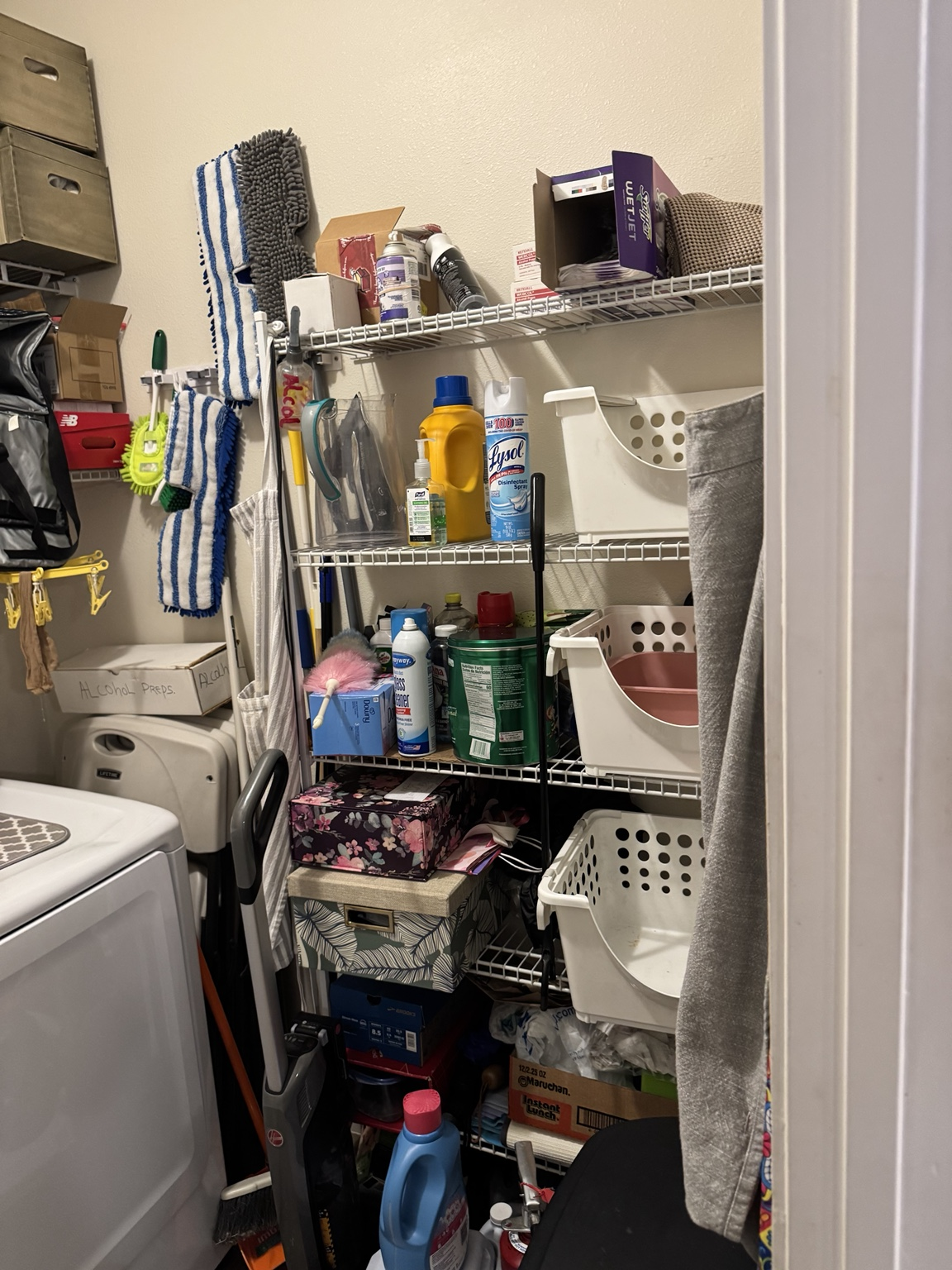 Utility closet packed with cleaning supplies, laundry baskets, mops and storage boxes
